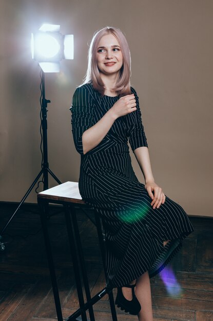 Portret van een jonge mooie vrouw in het licht flitst. Mooie blondevrouw in zwarte kleding