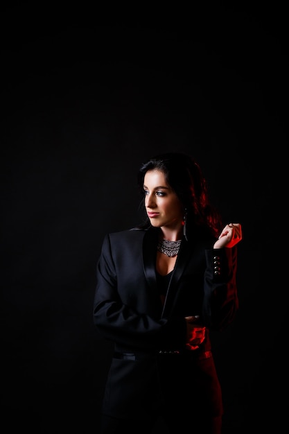 Portret van een jonge mooie vrouw met donker haar van Europees uiterlijk Gekleed in een zwarte jas Geïsoleerd op zwarte achtergrond