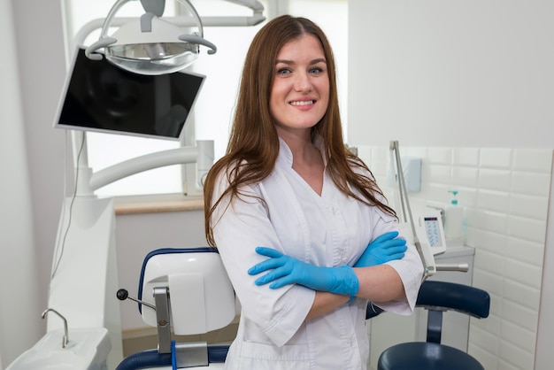 Portret van een jonge mooie vrouwelijke tandarts die in haar tandartspraktijk zit