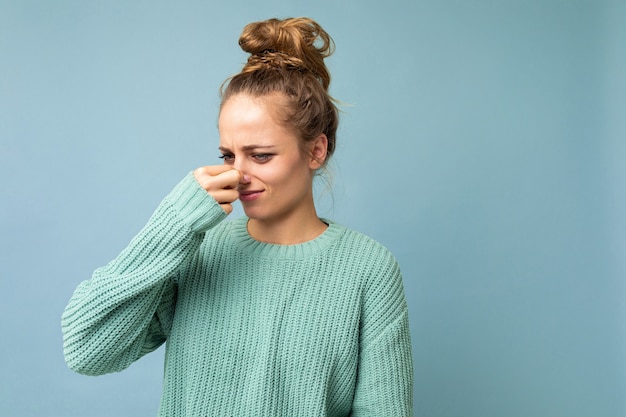 Portret van een jonge ontevreden mooie blonde vrouw met oprechte emoties die casual blauw draagt