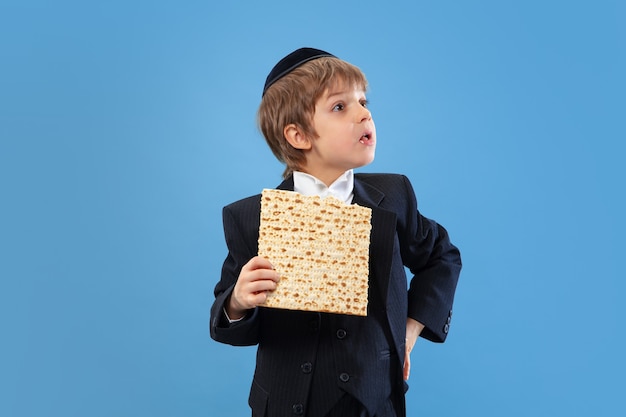 Portret van een jonge orthodoxe joodse jongen geïsoleerd op blauwe studio