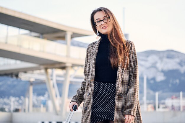 Portret van een jonge slimme zakenvrouw op internationale luchthaven met koffer