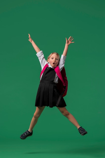 Foto portret van een jonge studente in schooluniform die in de lucht springt