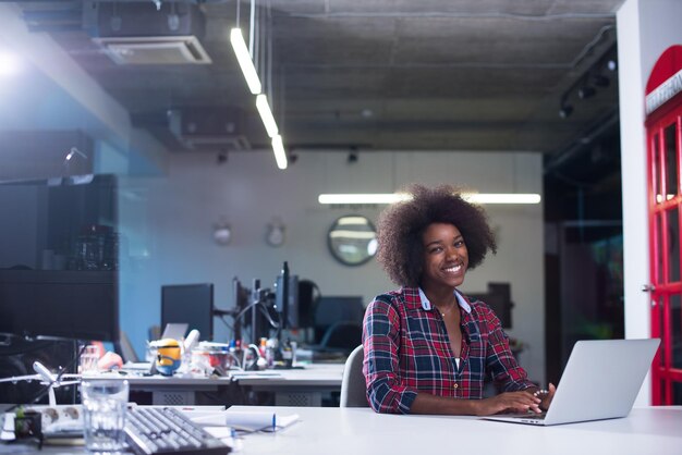 portret van een jonge, succesvolle Afro-Amerikaanse mooie vrouw die graag een goede en plezierige tijd doorbrengt terwijl ze in een groot, modern kantoor werkt