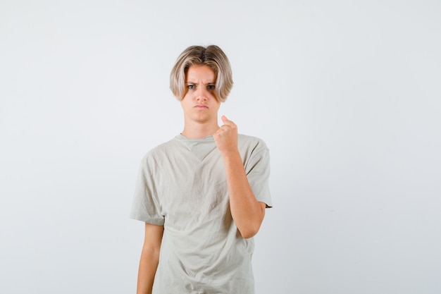 Portret van een jonge tienerjongen die gebalde vuist in t-shirt toont en woedend vooraanzicht kijkt