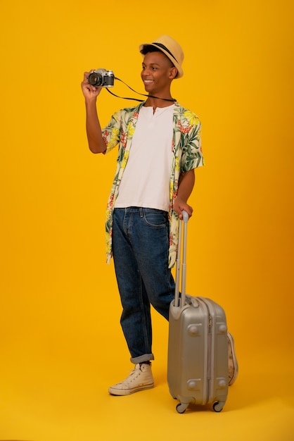 Portret van een jonge toeristische man die foto's maakt met een camera over geïsoleerde achtergrond. Reisconcept.
