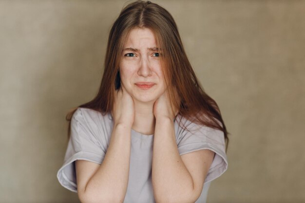 Portret van een jonge, verdrietige, overstuur blanke vrouw die naar de camera kijkt tegen een beige achtergrond Casting film film acteren audities