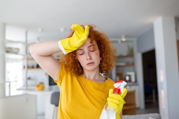 Portret van een jonge vermoeide vrouw met rubberen handschoenen die rust na het schoonmaken van een appartement Huishoudconcept