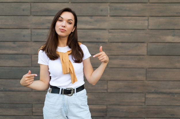 Portret van een jonge, vrolijke, positieve, mooie brunette vrouw met een trendy outfit die in de