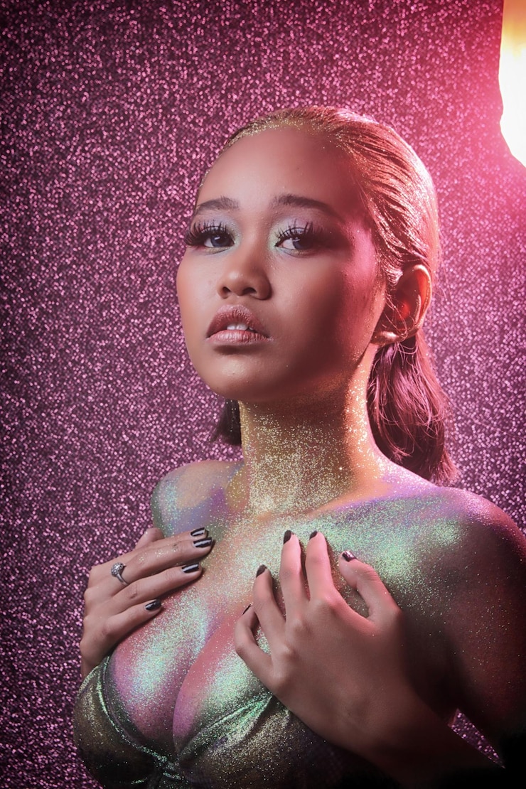 Foto portret van een jonge vrouw bedekt met glitter tegen de muur