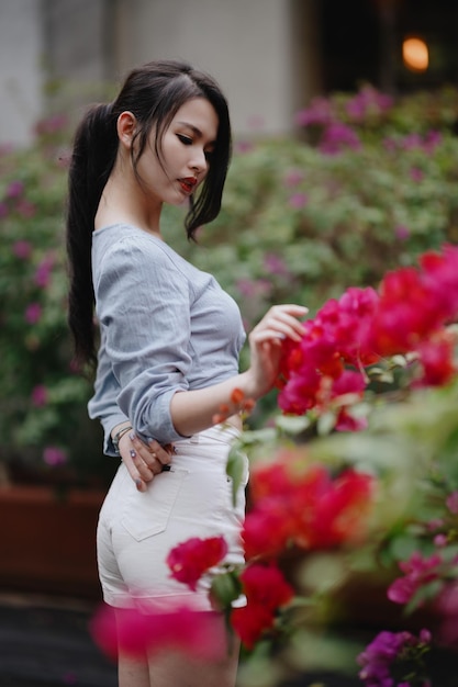 Portret van een jonge vrouw die bij bloeiende planten staat