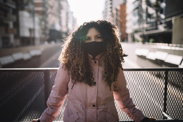 Portret van een jonge vrouw die bij een reling in de stad staat