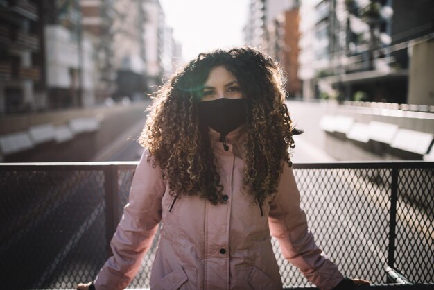 Foto portret van een jonge vrouw die bij een reling in de stad staat