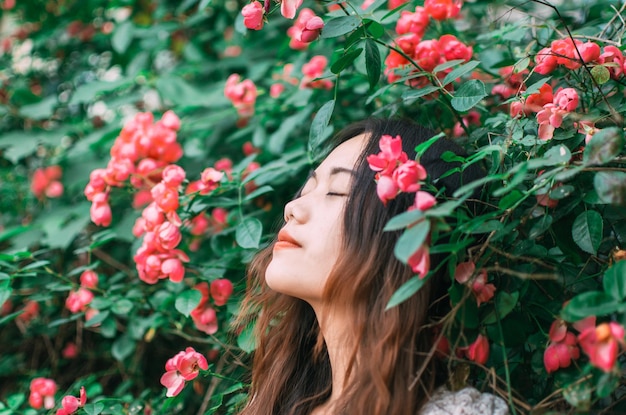Portret van een jonge vrouw die dagdromen bij een bloemenstruik