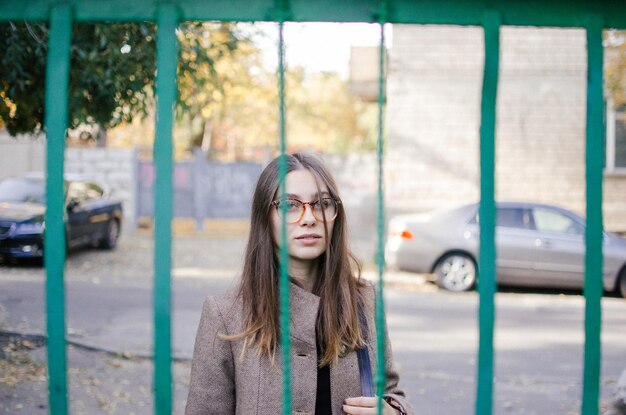 Foto portret van een jonge vrouw die door de poort kijkt