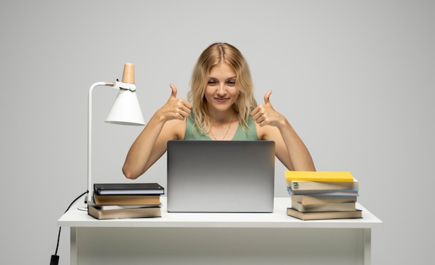 Portret van een jonge vrouw die een digitale tablet gebruikt terwijl ze tegen een witte achtergrond staat