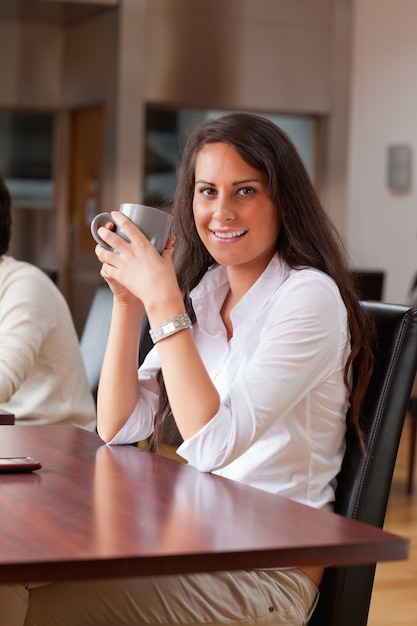 Portret van een jonge vrouw die een koffie heeft