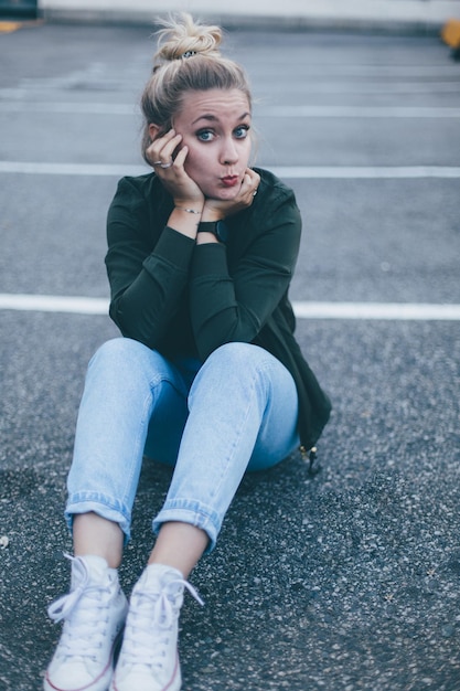 Portret van een jonge vrouw die een mobiele telefoon gebruikt terwijl ze op de weg zit