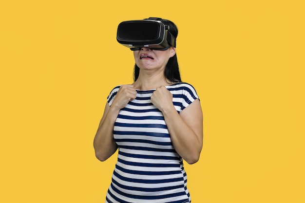 Portret van een jonge vrouw die een vr-headset draagt, is bang voor iets geïsoleerd op een gele achtergrond