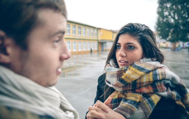 Portret van een jonge vrouw die excuses vraagt aan de beledigde man na een harde ruzie buitenshuis. Paar relaties en problemen concept.