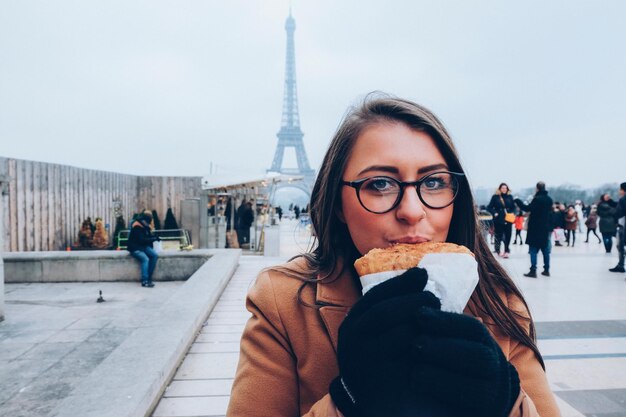 Foto portret van een jonge vrouw die in de stad eet