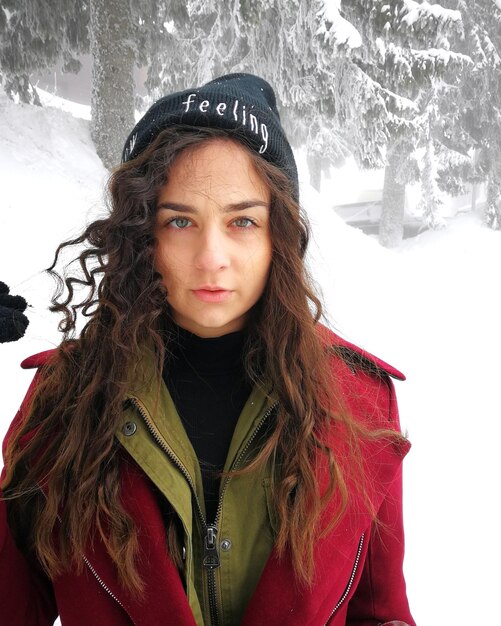 Foto portret van een jonge vrouw die in de winter in het bos staat