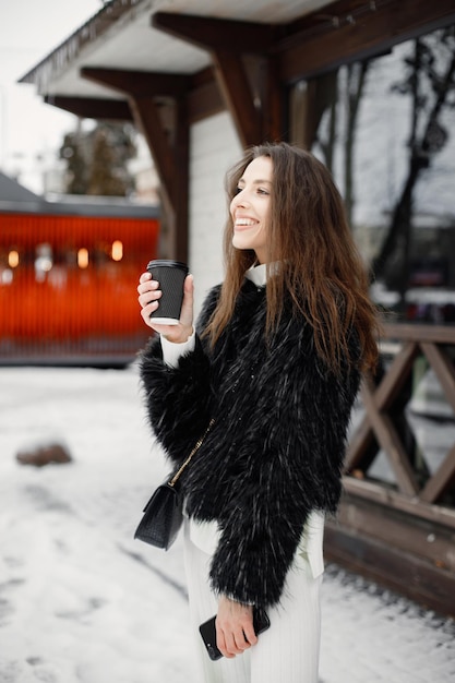 Portret van een jonge vrouw die in de winterstad staat en poseert voor een foto