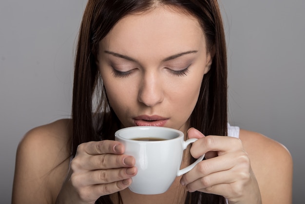 Portret van een jonge vrouw die koffie drinkt.