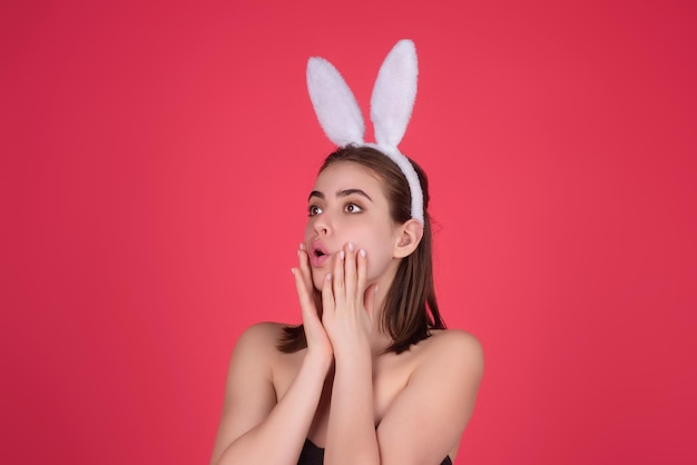 Portret van een jonge vrouw die konijntjesoren draagt en paaseieren vasthoudt over een geïsoleerde achtergrond in de studio