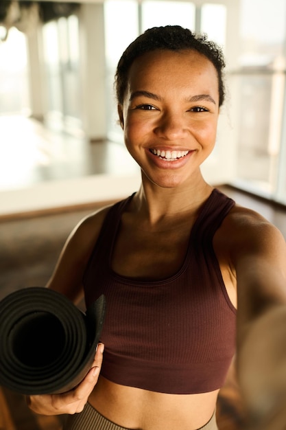 Portret van een jonge vrouw die lacht naar de camera die ze selfie portret maakt in de sportschool