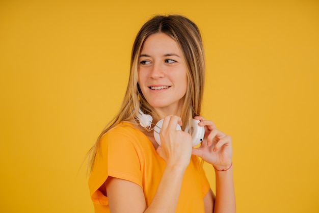 Portret van een jonge vrouw die lacht terwijl ze poseert met een koptelefoon tegen een geïsoleerde achtergrond.