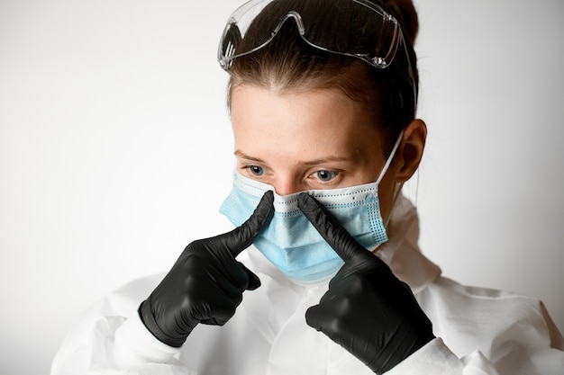 Portret van een jonge vrouw die medische masker met haar vingers regelen