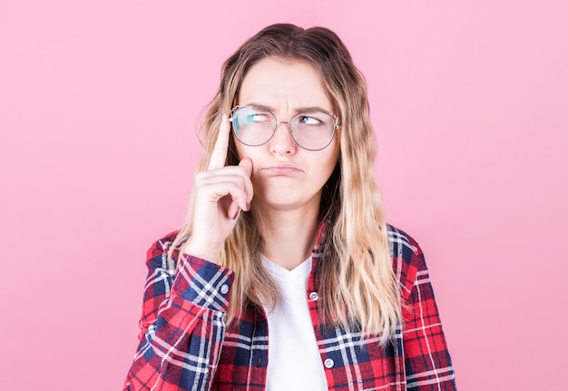 Portret van een jonge vrouw die met haar vinger aan haar hoofd denkt en naar de kant kijkt