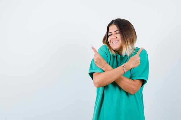 Portret van een jonge vrouw die naar tegenovergestelde richtingen wijst met gekruiste armen in polo-t-shirt en er zalig vooraanzicht uitziet