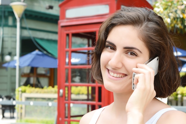 Foto portret van een jonge vrouw die op de telefoon spreekt.