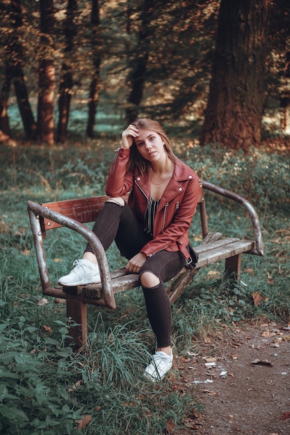 Portret van een jonge vrouw die op een bankje in het bos zit