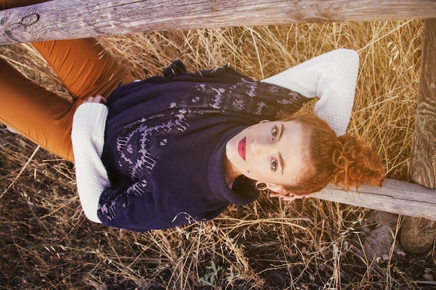 Portret van een jonge vrouw die op een reling in het veld ligt