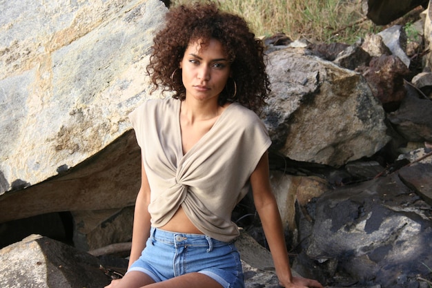 Foto portret van een jonge vrouw die op een rots zit