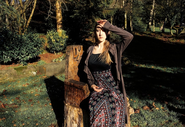 Portret van een jonge vrouw die op een stoel in het bos zit