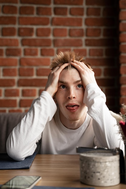 Foto portret van een jonge vrouw die op een tafel tegen een bakstenen muur zit