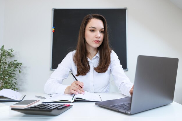 Portret van een jonge vrouw die op haar laptop op kantoor werkt