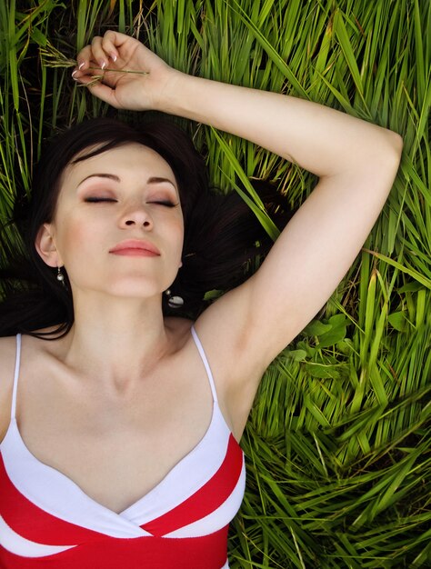 Foto portret van een jonge vrouw die op het gras ligt