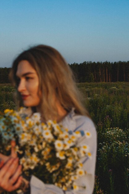 Foto portret van een jonge vrouw die op het veld staat tegen een heldere hemel