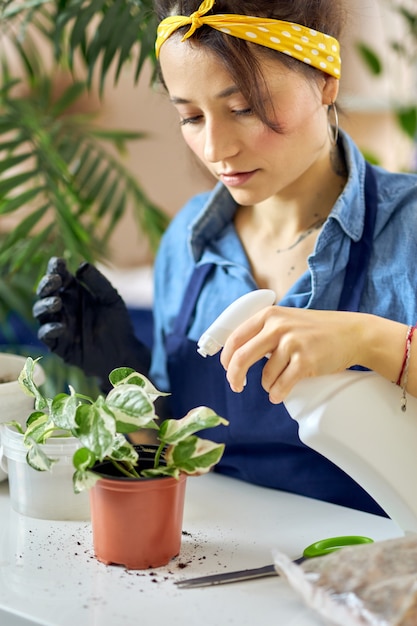 Portret van een jonge vrouw die 's morgens thuis planten sproeit met een spuitfles tijdens het water geven