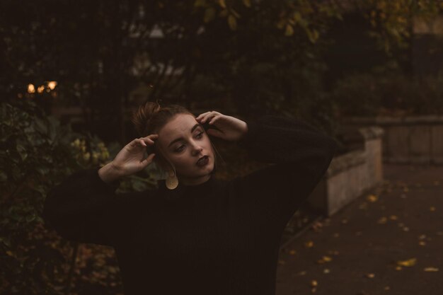 Portret van een jonge vrouw die's nachts tegen bomen staat