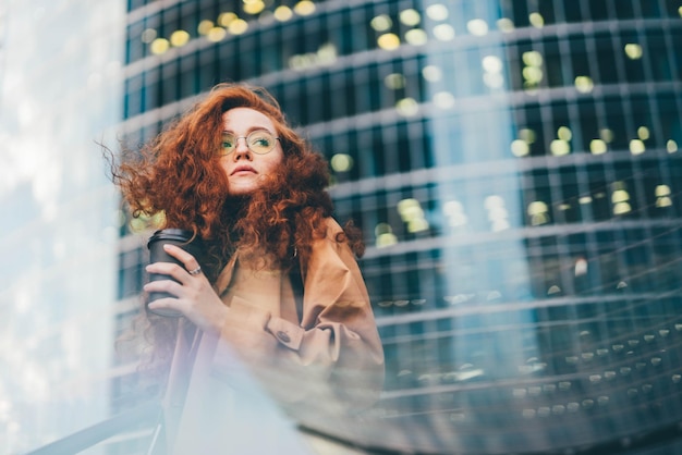 Foto portret van een jonge vrouw die's nachts tegen een verlichte stad staat