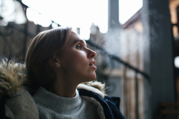 Portret van een jonge vrouw die stoom uit haar mond op een koude winterdag buiten laat