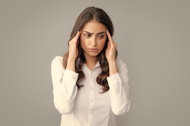 Portret van een jonge vrouw die stress of spanningshoofdpijn voelt Uitgeput vermoeid meisje wanhopig en gestrest omdat pijn en migraine Boos verdrietig depressief model met handen op het hoofd