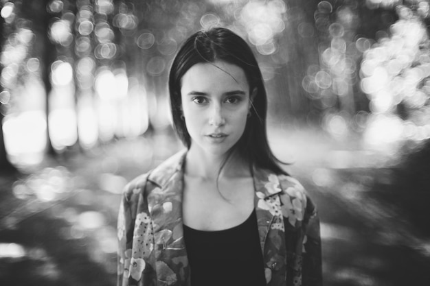 Portret van een jonge vrouw die tegen bomen staat