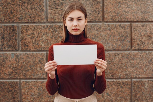 Foto portret van een jonge vrouw die tegen de muur staat